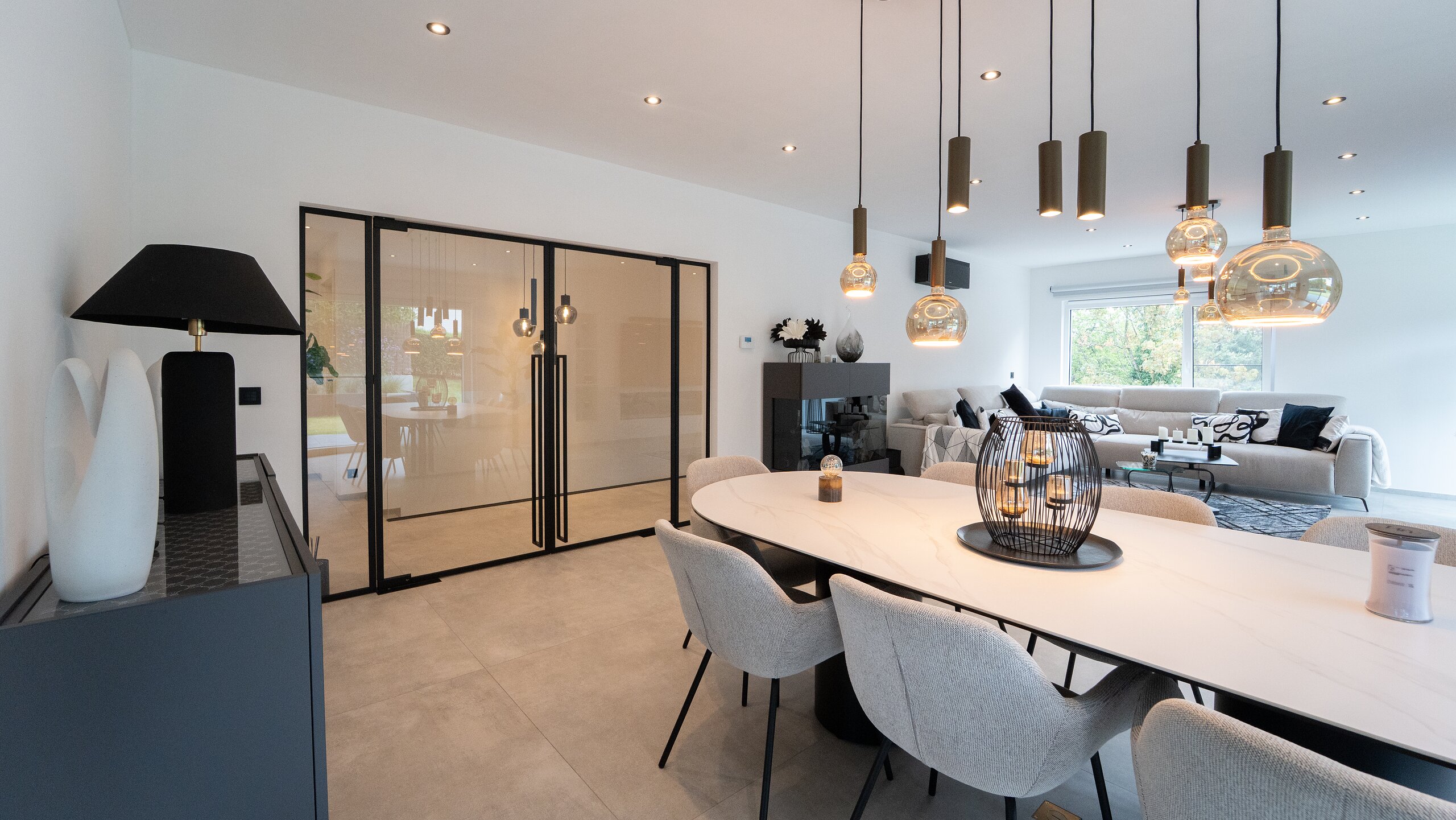 Double porte vitrée à profilés noirs façon atelier entre salle à manger et salon d'une maison contemporaine