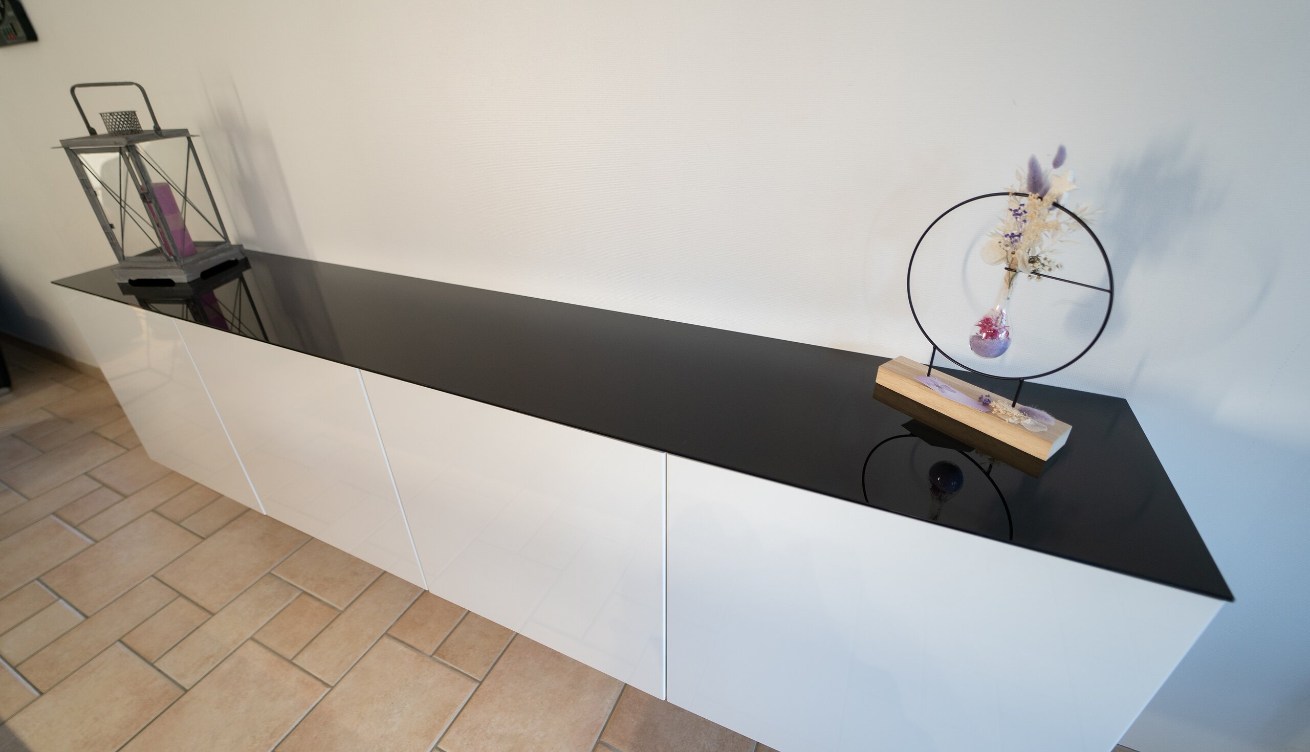 Meuble bas blanc surmonté d’un plateau en verre noir laqué, décoré d’une lanterne et d’un objet design