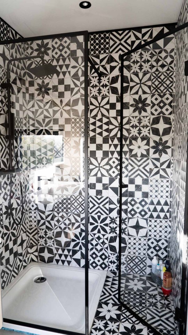 Paroi de douche Steel Look à profilés noirs devant un carrelage noir et blanc