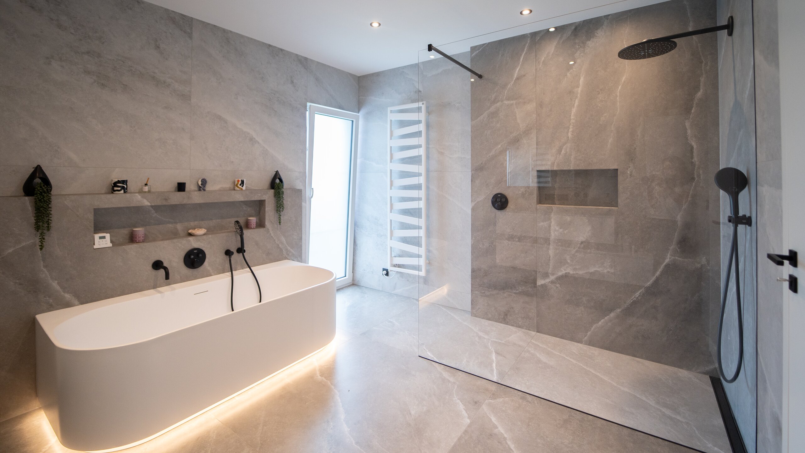 Paroi de douche fixe en verre clair avec barre de stabilisation noire dans une salle de bain en marbre gris