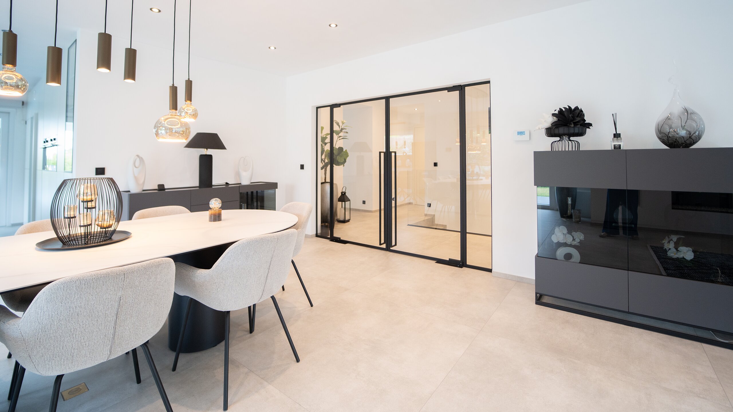 Portes en verre clair à profilés noirs et poignées tubulaires au fond d'une salle à manger lumineuse
